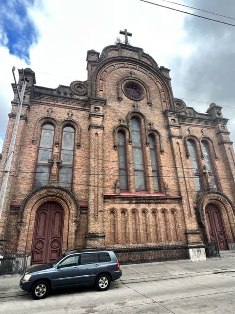 A car is parked in front of a large brick building.