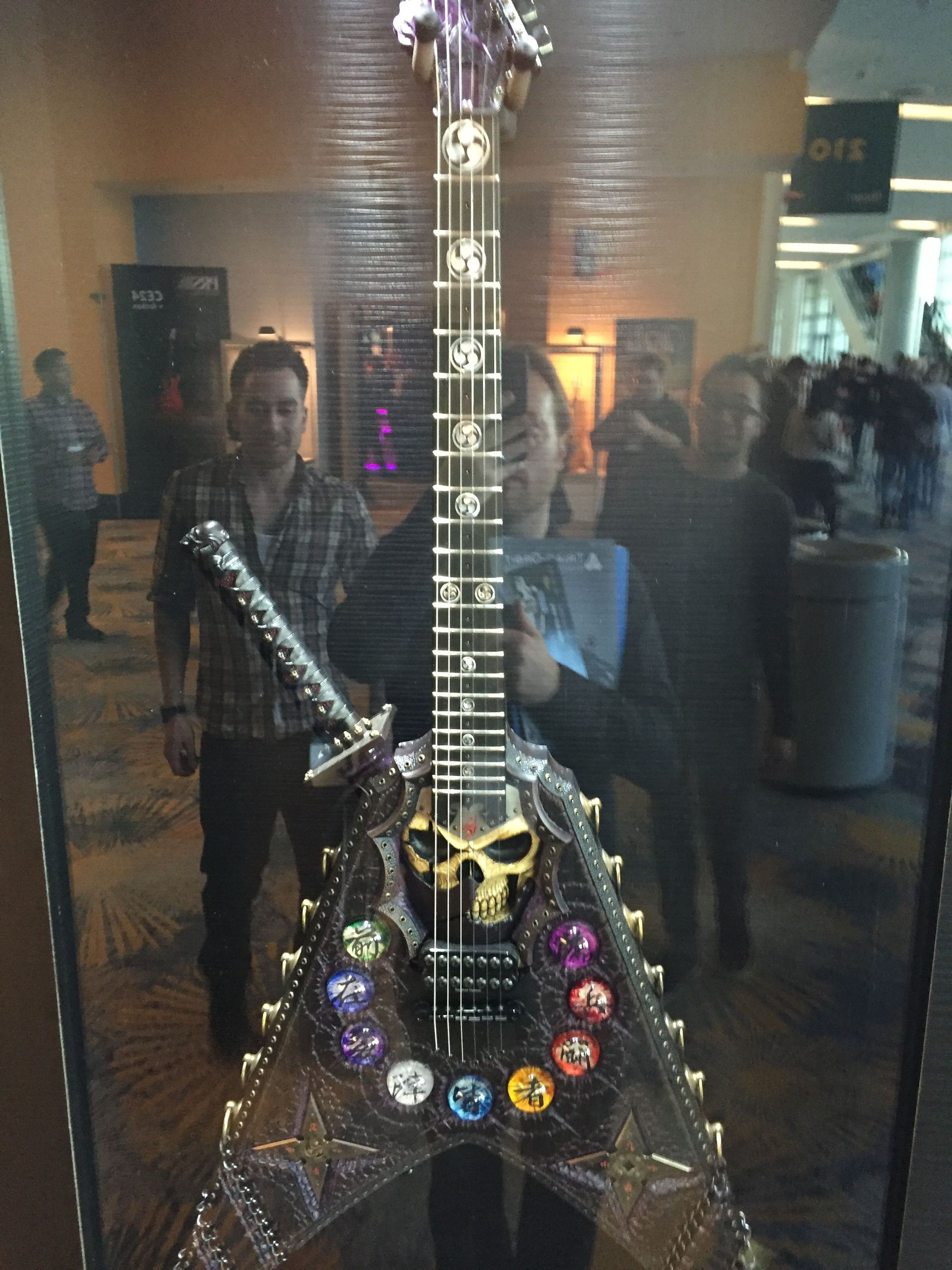 A man stands in front of a guitar with a skull on it