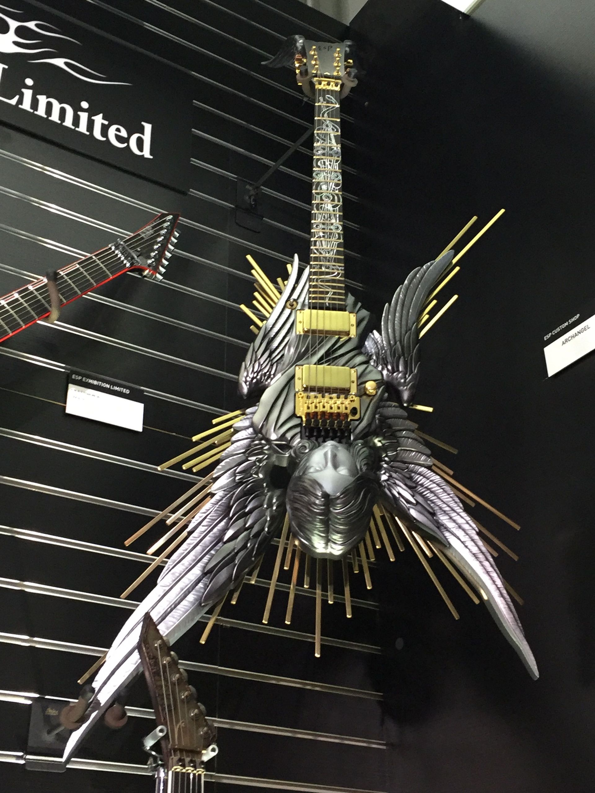 A guitar with wings is on display in front of a sign that says limited