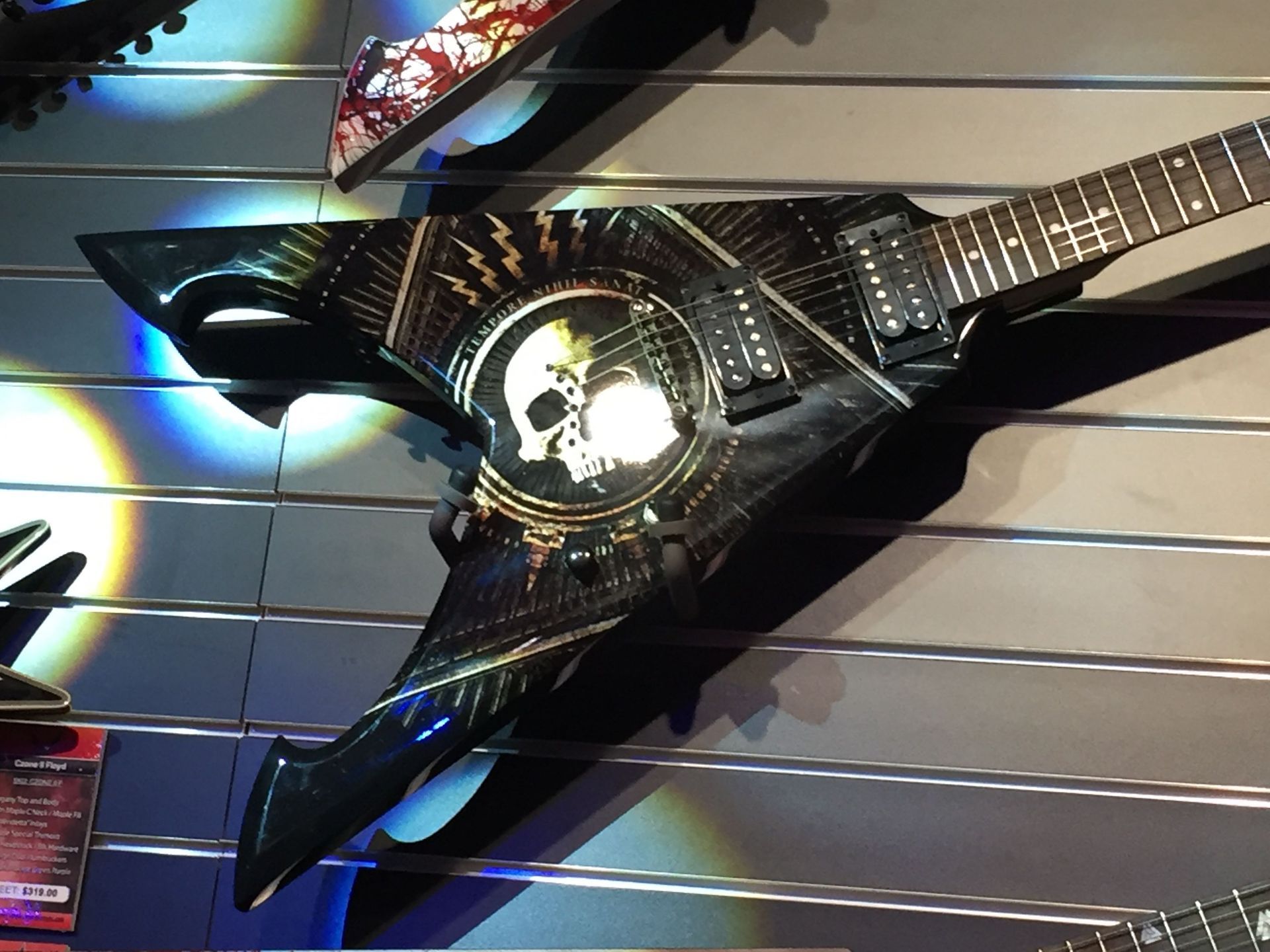 A guitar with a skull on it is hanging on a wall