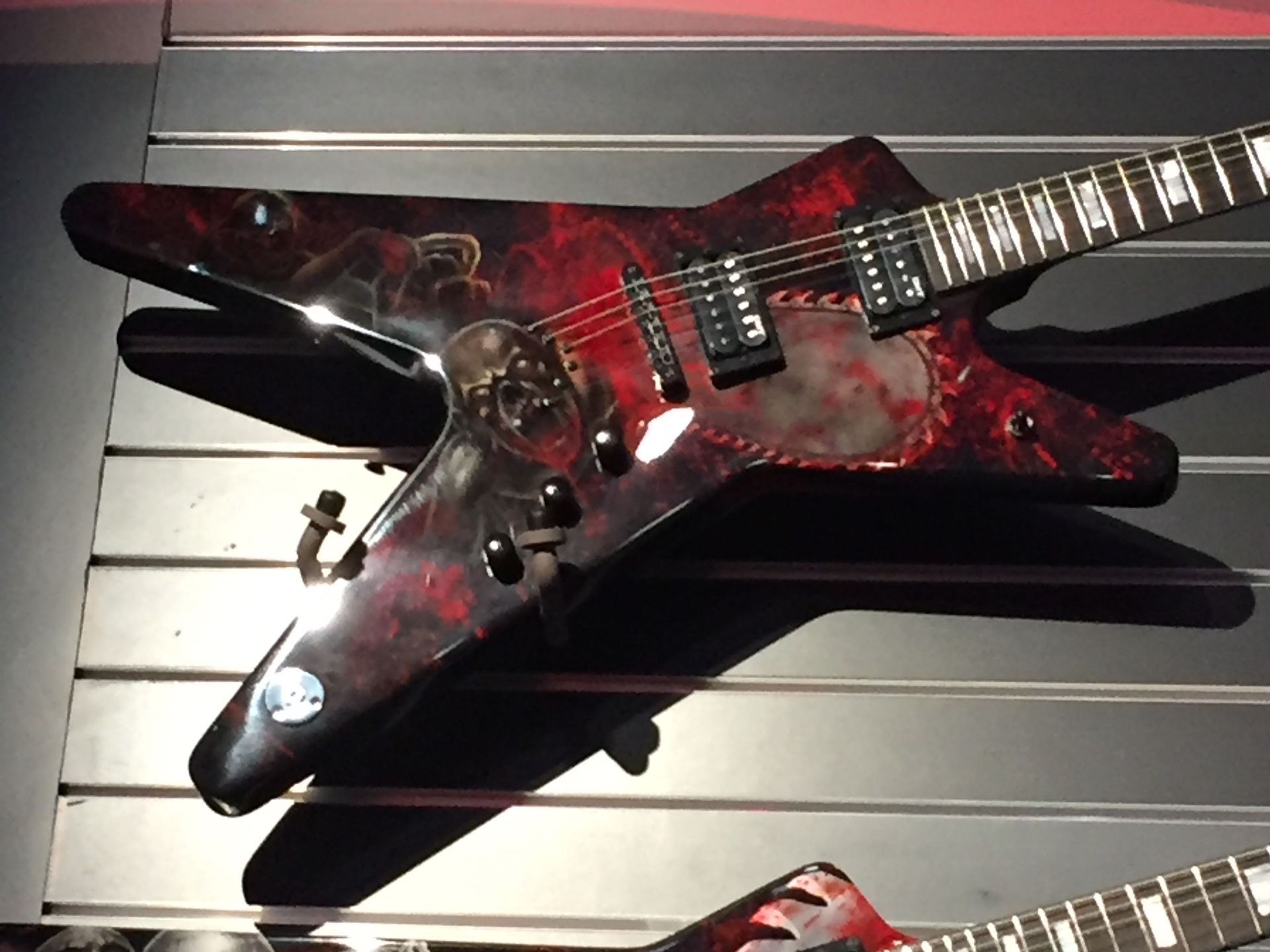 A red and black guitar is on display on a wall