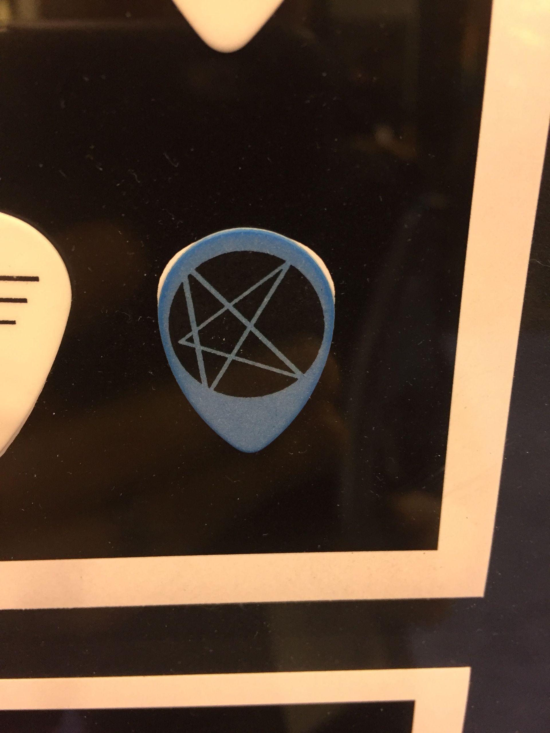 A picture of a guitar pick with a pentagram on it