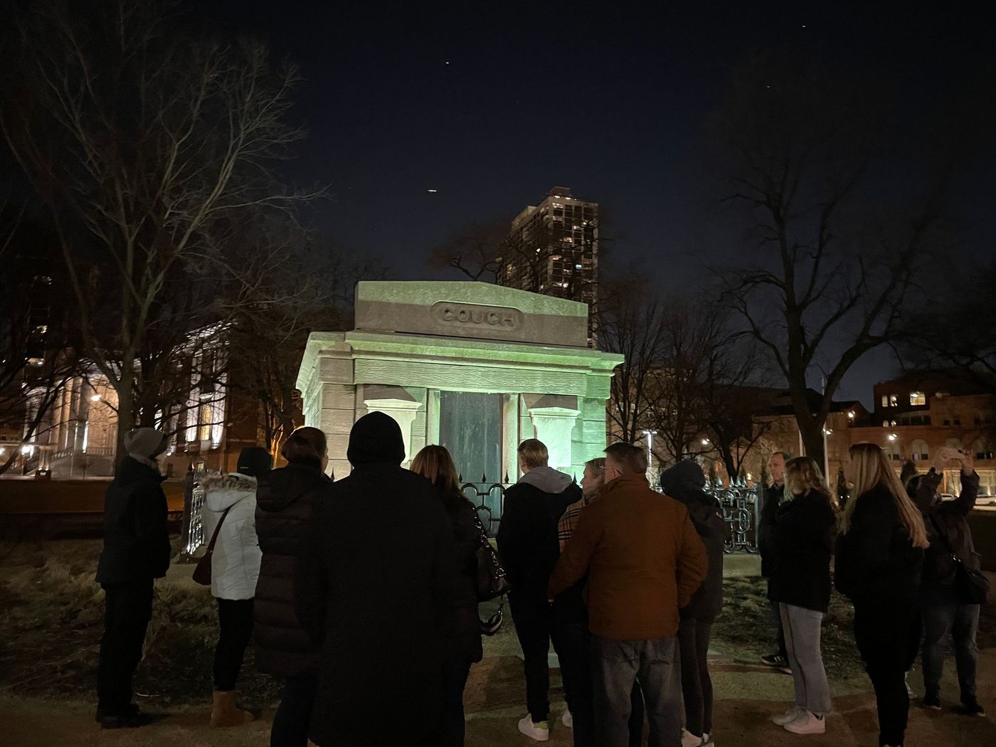 A group of people are standing in front of a building at night.