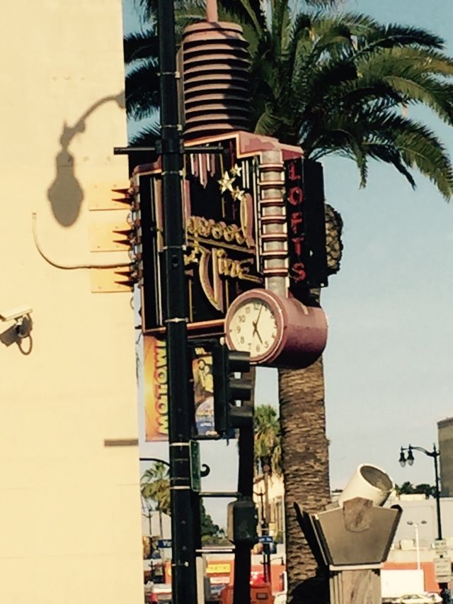 A clock on a pole with a sign that says ' hollywood ' on it