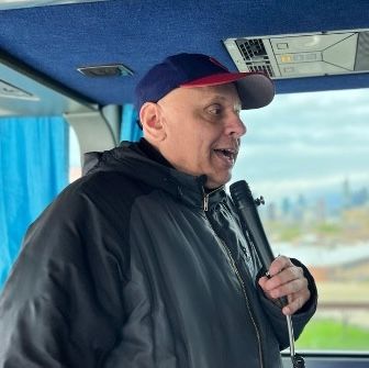 A man wearing a hat and a jacket is sitting in a bus.