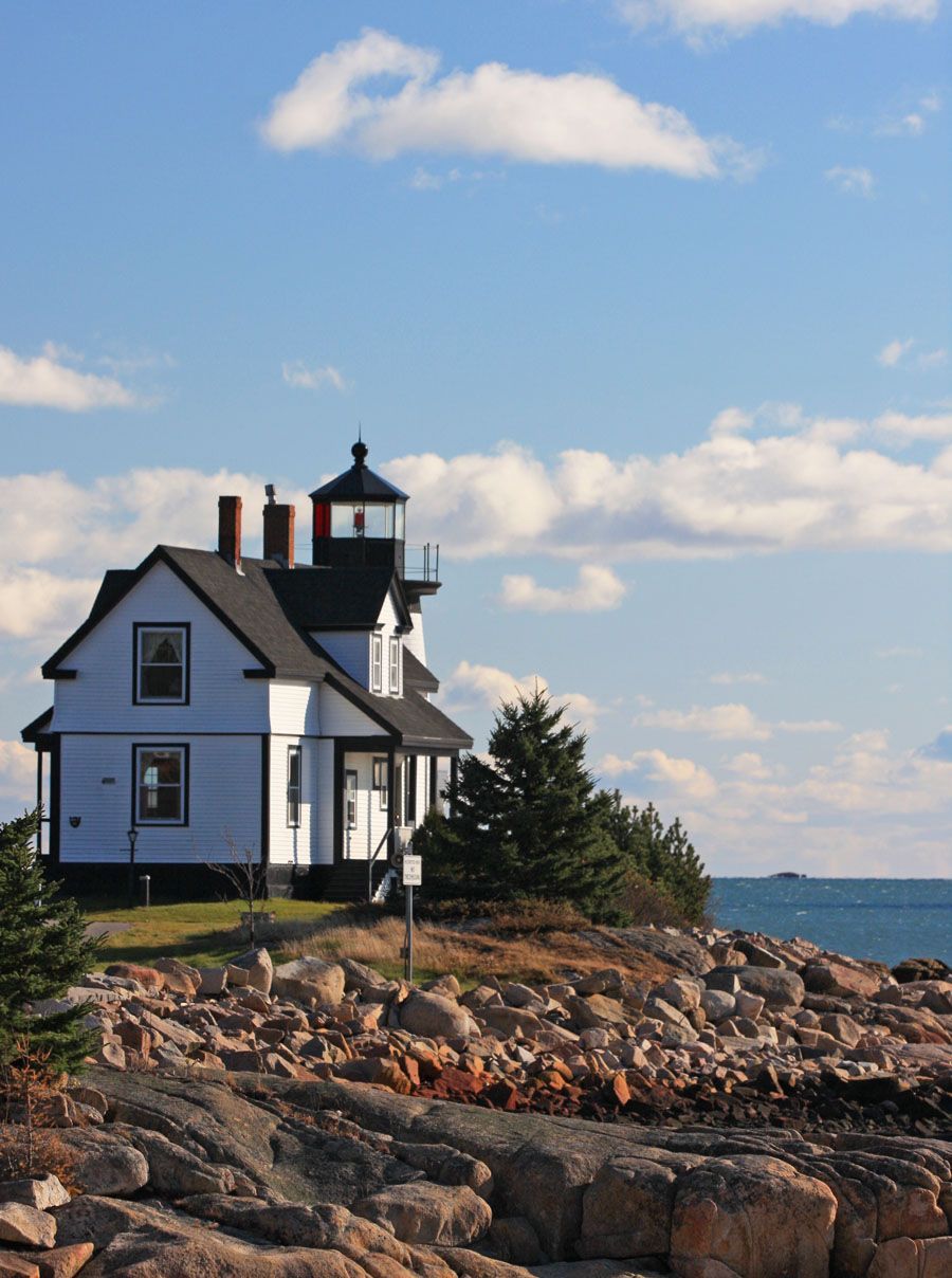 A white house sits on a rocky hill overlooking the ocean