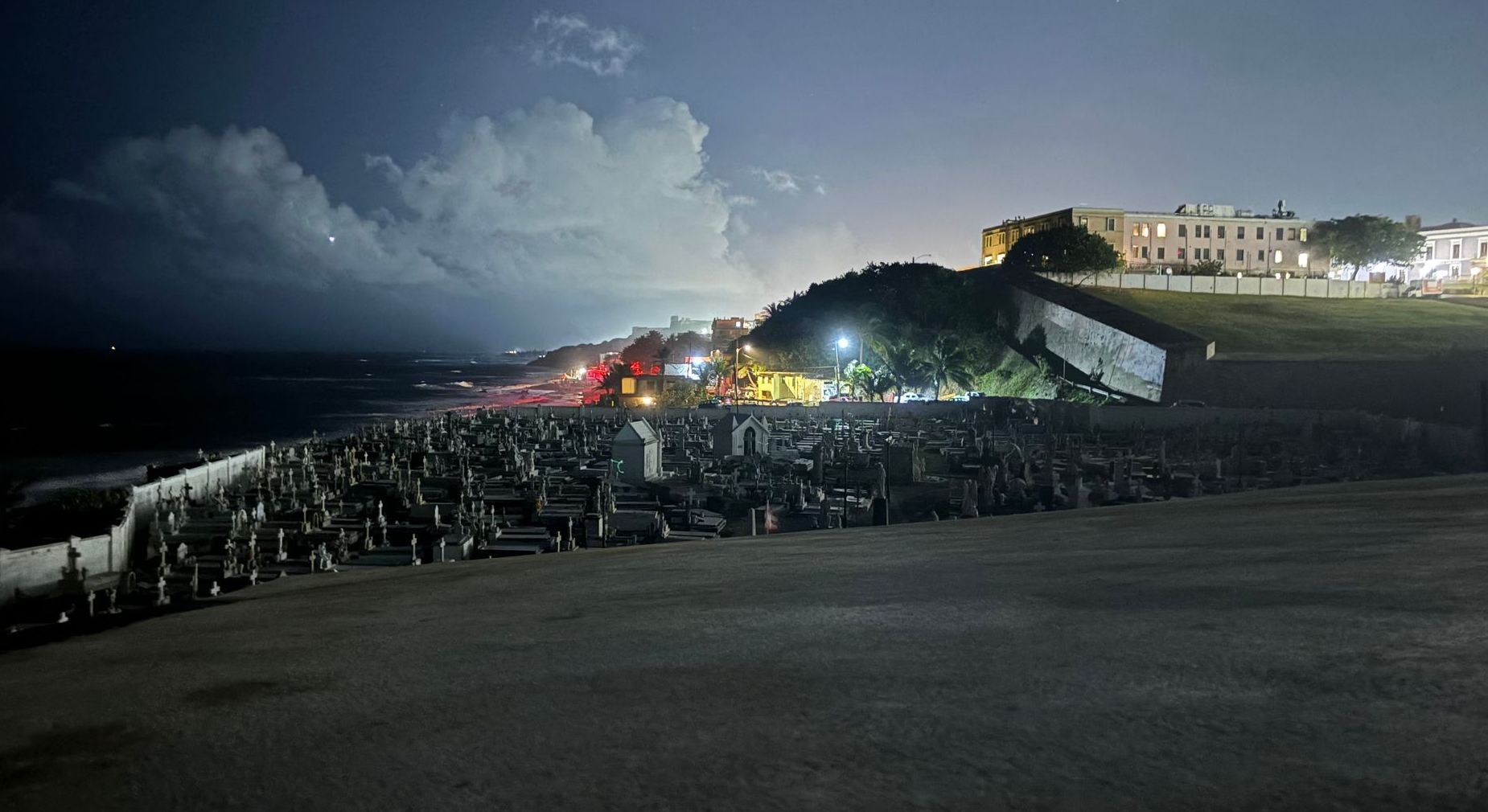 A large group of people are gathered on a beach at night