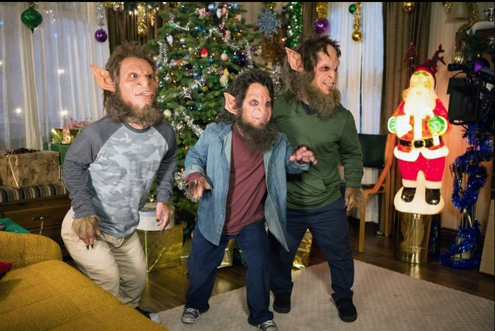 Three men dressed as werewolves are standing in front of a christmas tree.