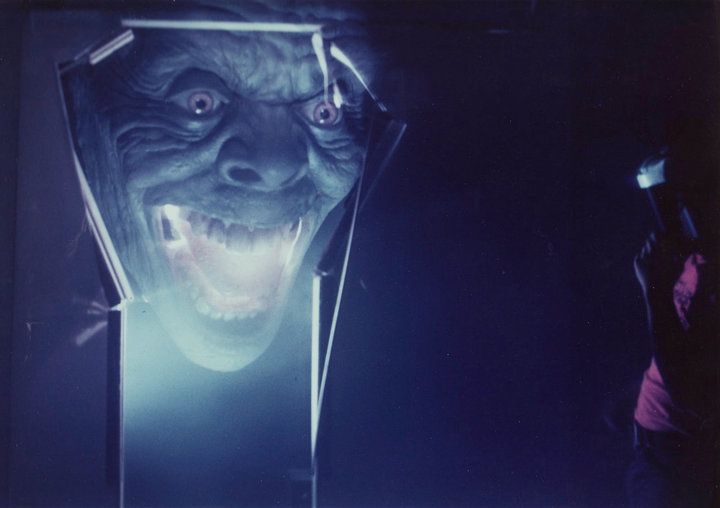 A close up of a monster 's face in a dark room.