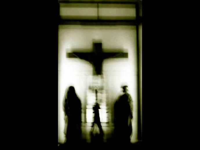 A group of people are standing in front of a cross.