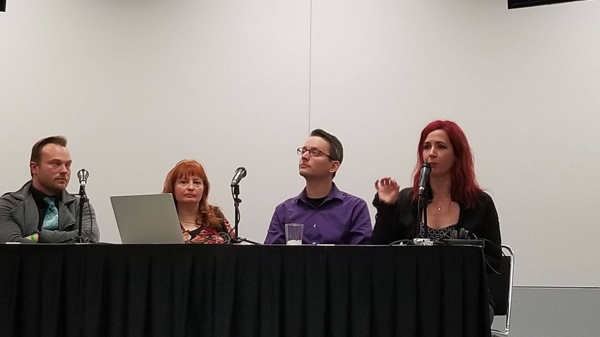 A group of people are sitting at a table with microphones.