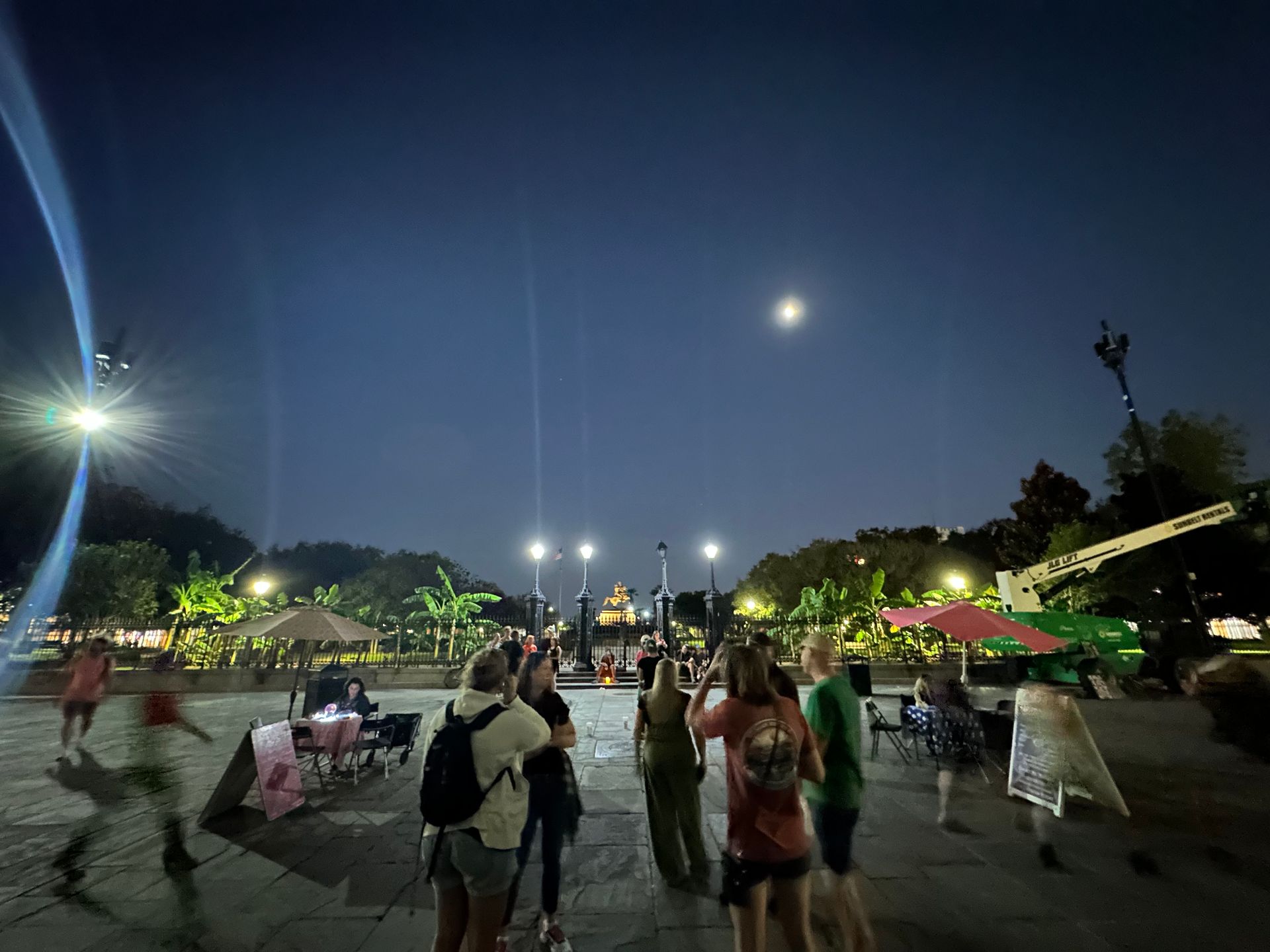 A group of people explores a town plaza at night