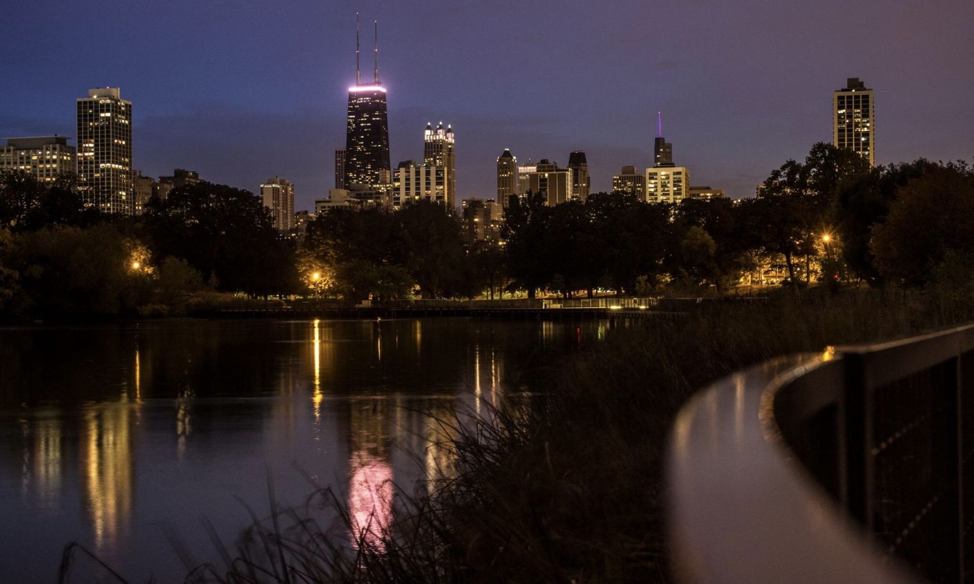 A city skyline is reflected in a lake at night