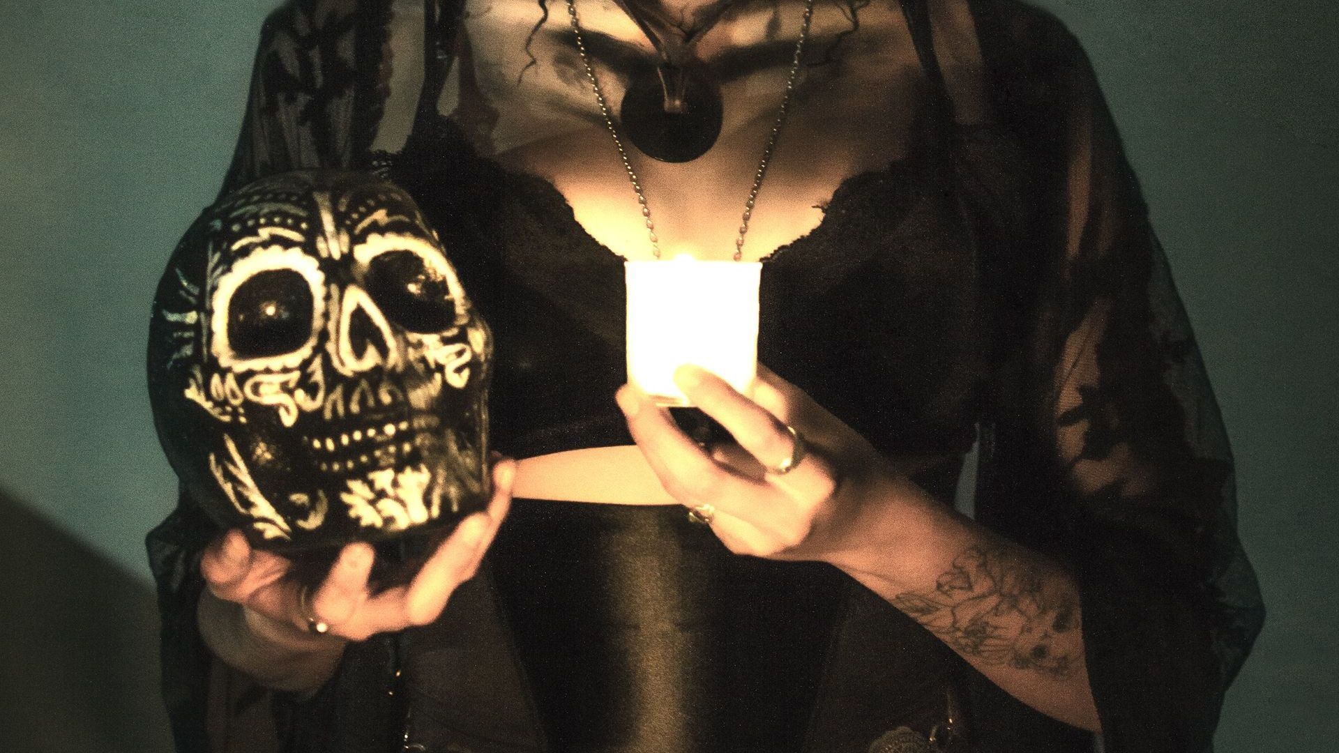 A woman is holding a skull and a candle in her hands