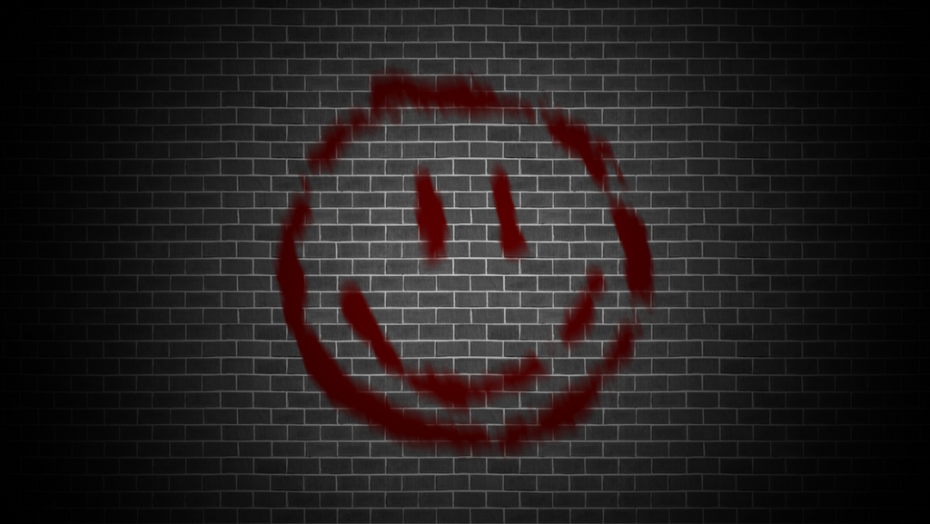 A red smiley face is painted on a black brick wall.