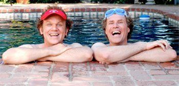 Two men are laying on the edge of a swimming pool.