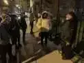 A group of people are walking down a street at night.