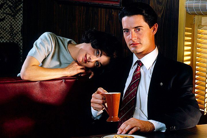 A man and a woman are sitting at a table with a cup of coffee.