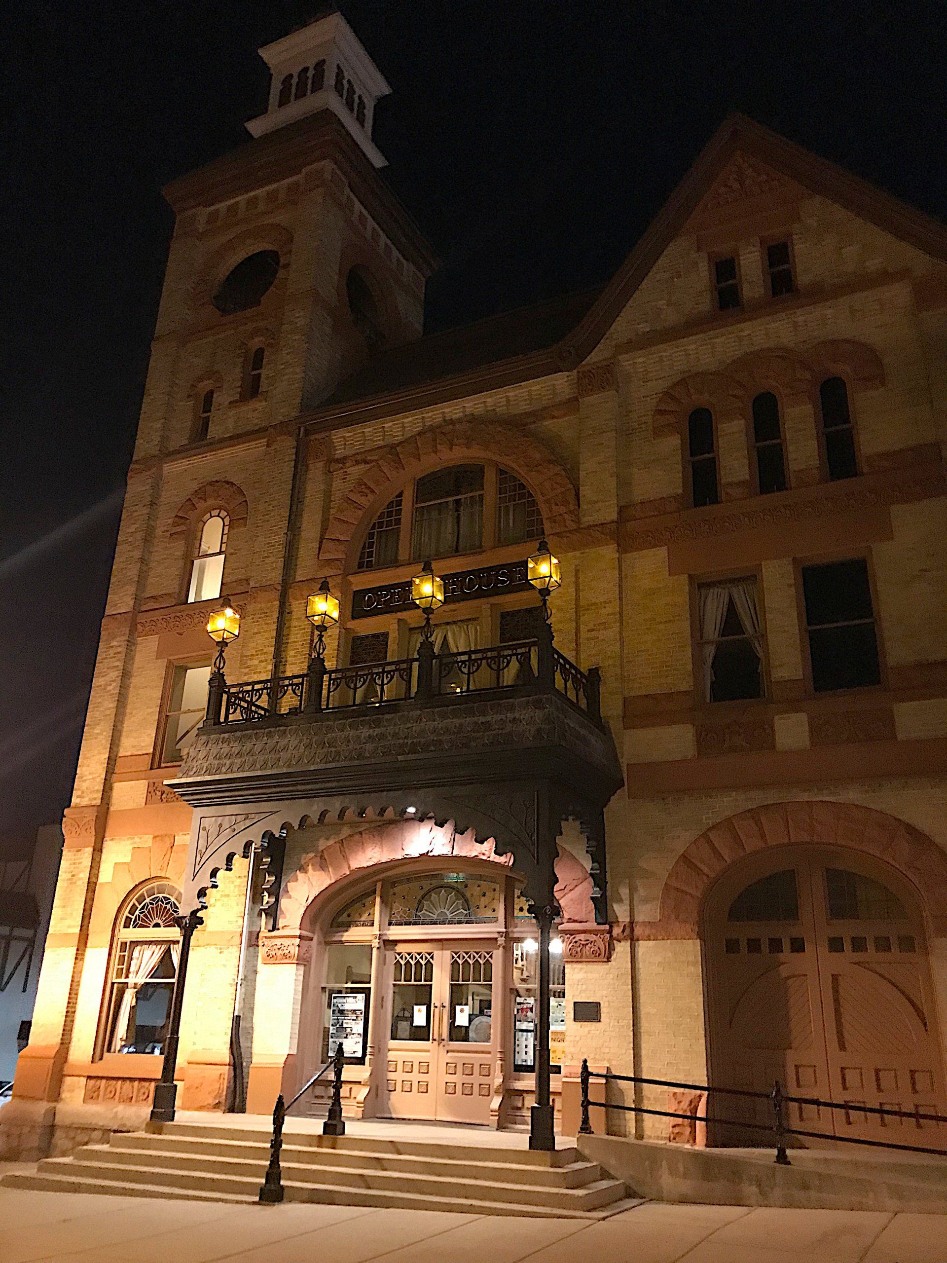 A large building with a clock tower and a balcony at night