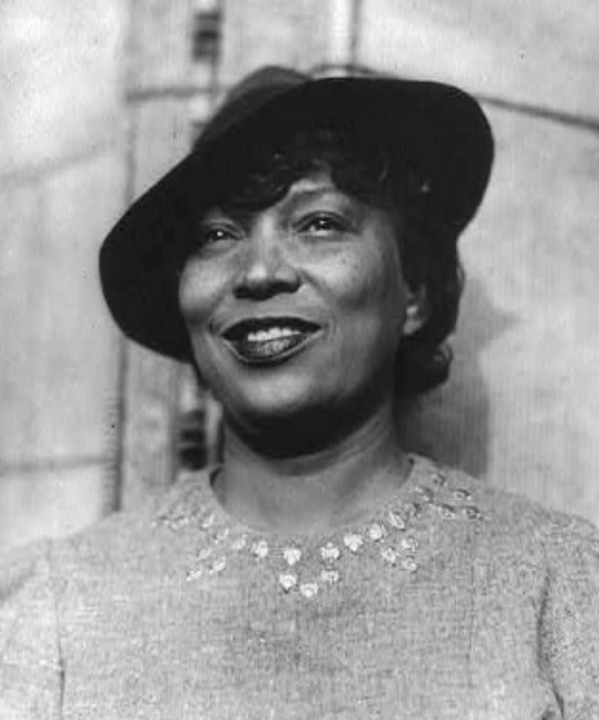 A black and white photo of a woman wearing a hat and smiling.