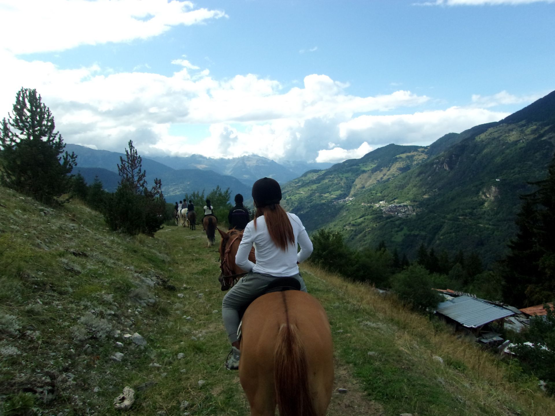 Un groupe de jeunes qui font du cheval sur un chemin entre les montagnes