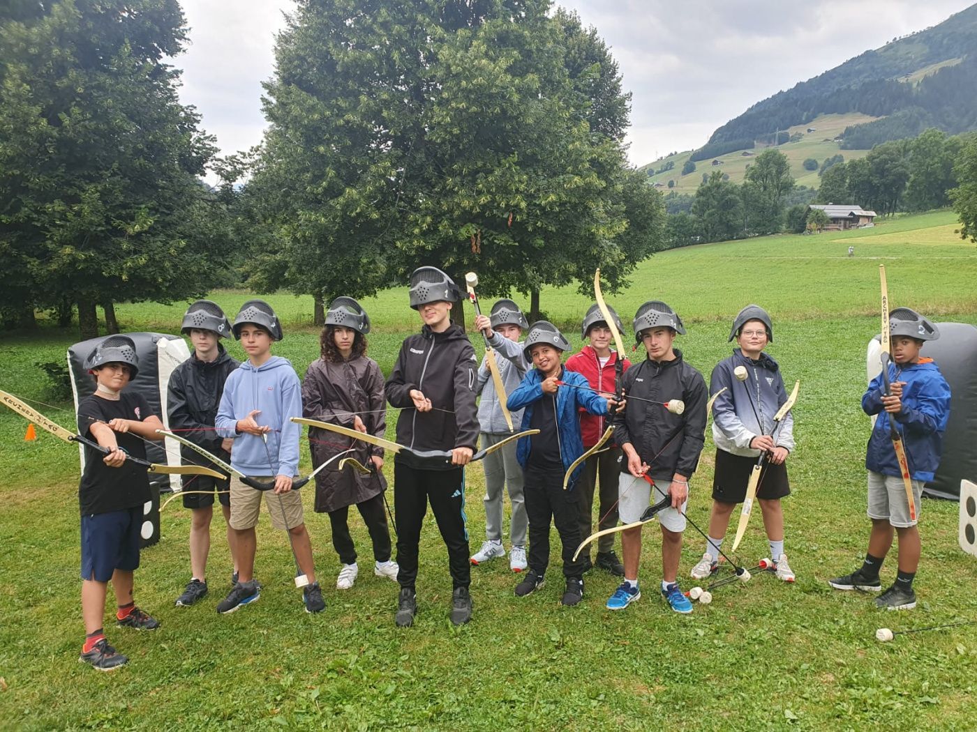 Un groupe d'enfants sont debout sur l'herbe avec un arc et des flèches en mains