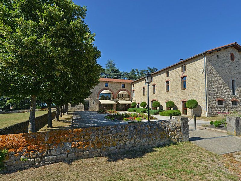 Un grand bâtiment à base de pierre entouré d'un grand espace avec des arbres devant