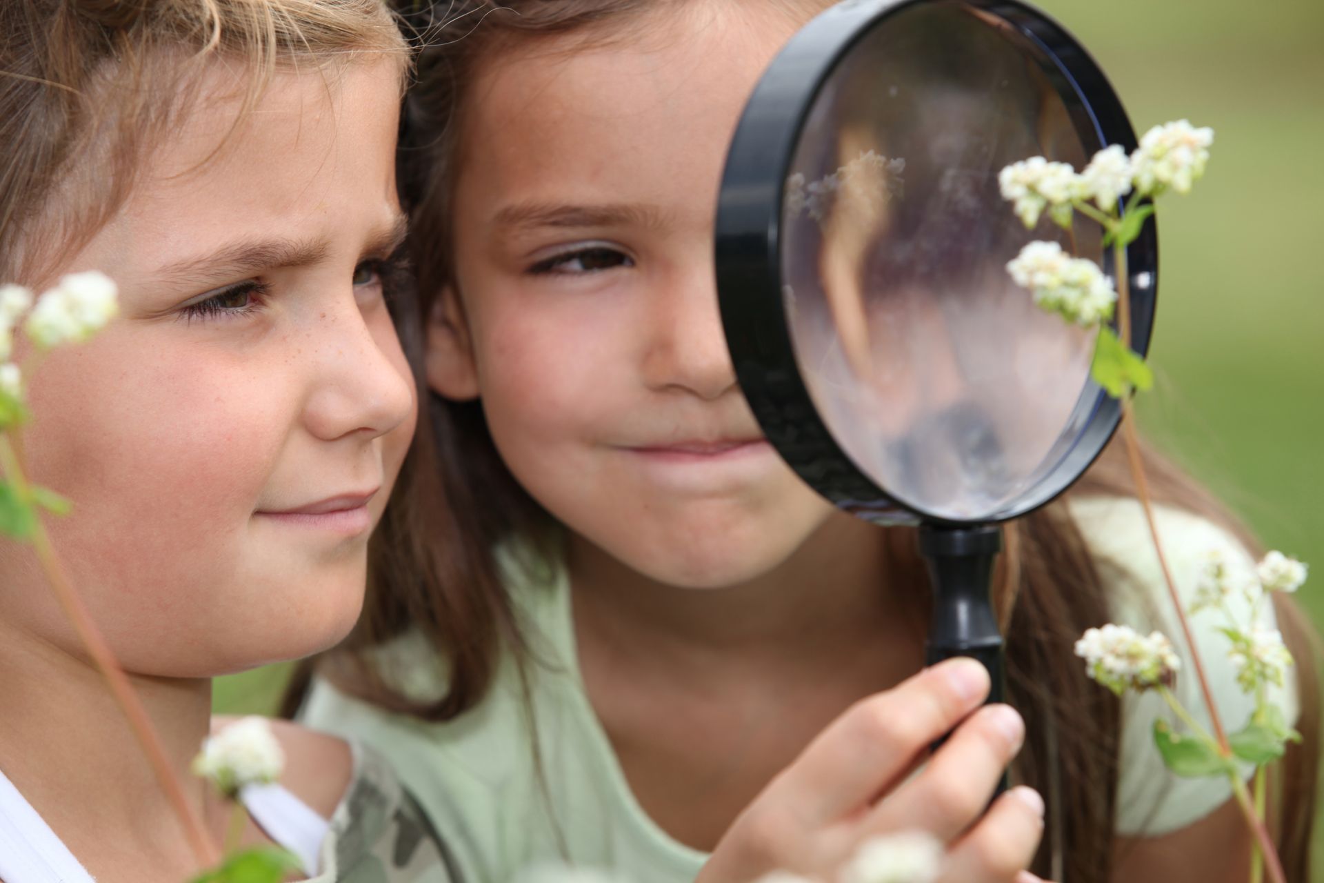Un jeune garçon et une jeune fille qui observent la  nature à travers une loupe