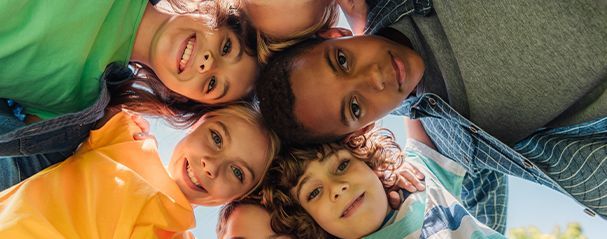Un groupe d'enfants qui se tiennent en cercle et qui font un grand sourire