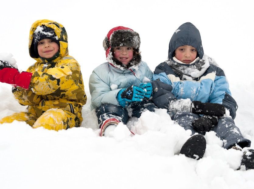 Des enfants en combinaison de ski jouent dans la neige