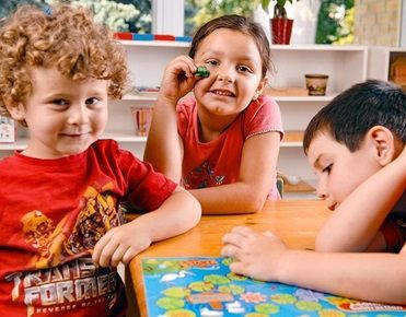 Des enfants attablés jouent à un jeu de société