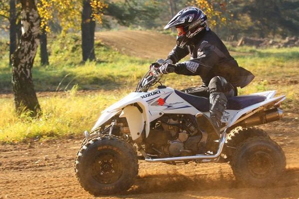 Un adolescent en casque se tient sur un quad dans la nature