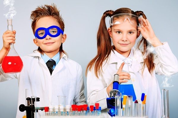 Deux enfants en blouse de scientifique font des expériences avec des tubes à essai