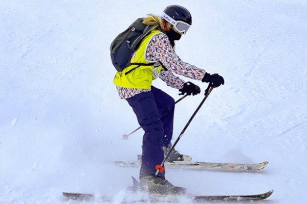 Une adolescente casquée fait du ski dans la neige avec des bâtons