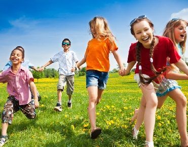 des enfants riants se tiennent la main dans une prairie au printemps