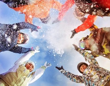 Des enfants vus d'en bas lèvent les bras en jetant de la neige