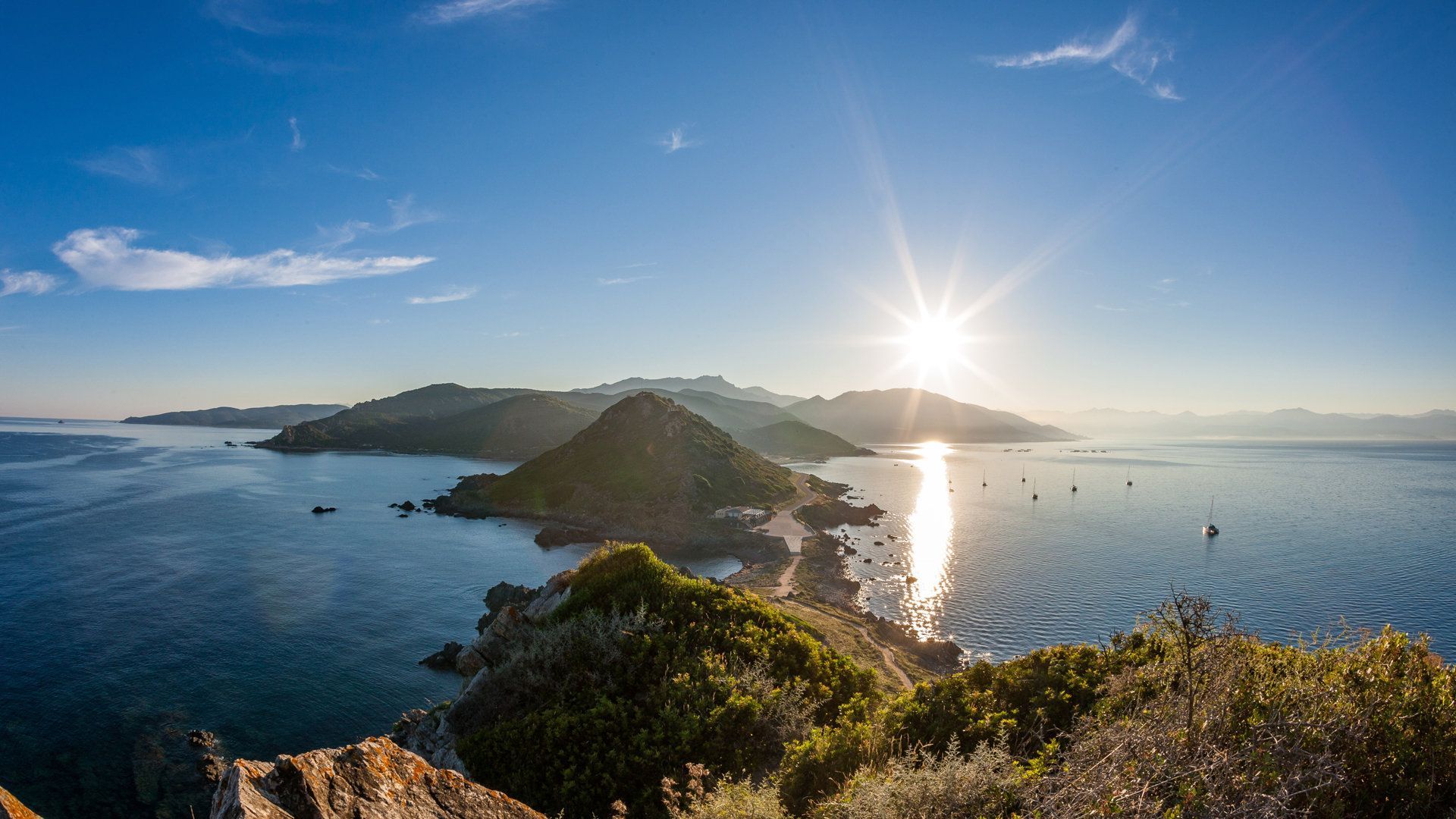 La soleil au dessus de la mer avec une chaîne de montagne en fond
