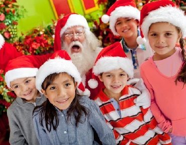 Des enfants avec un bonnet de Noël posent avec un Père Noël