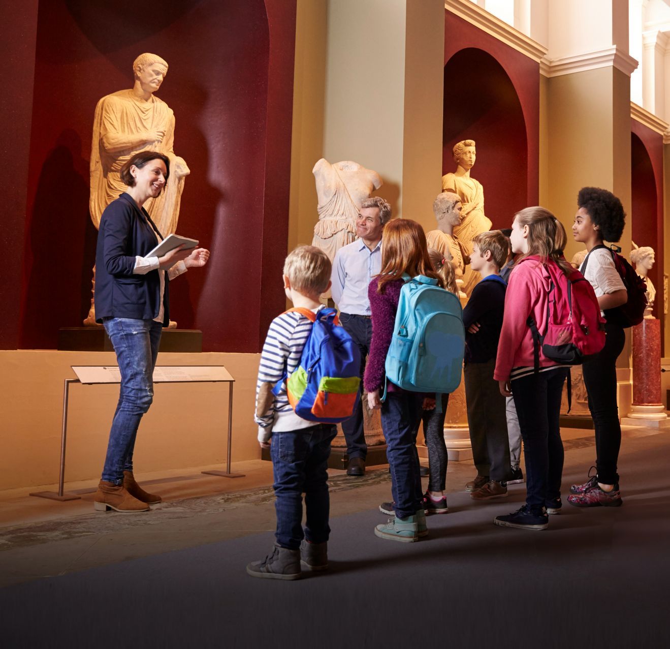 Un groupe d'enfants dans un musée en train d'écouter une professionnelle