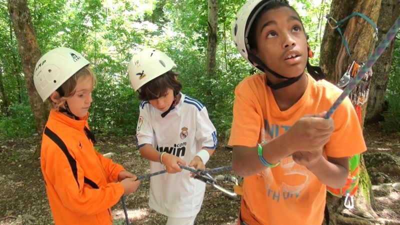 Des enfants portant un casque sécurisent une corde pour une activité escalade
