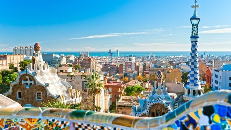 Une vue des toits de Barcelone depuis une terrasse décorée en carreaux de couleurs dans le style de Gaudi