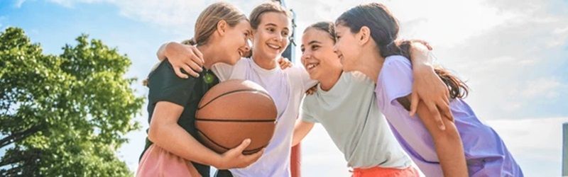 4 jeunes filles se tiennent dans les bras avec un ballon de basketball