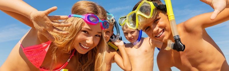 4 enfants portant masques et tubas sourient sur la plage