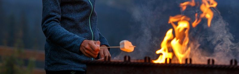 Un enfant fait griller un chamallow au-dessus d'un feu de camp 