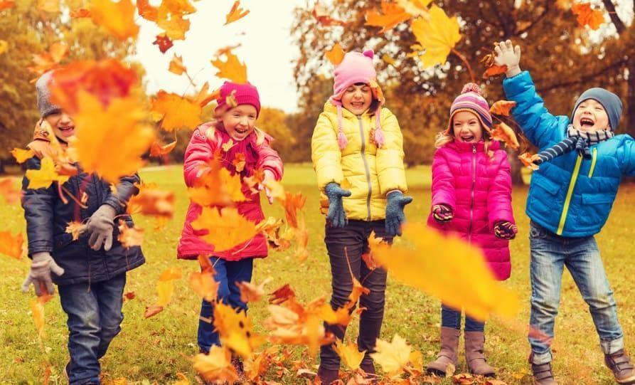 Des enfants jouent avec les feuilles en automne