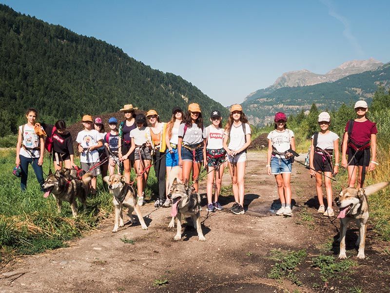 Un groupe d'enfants en train de faire de la cani-rando devant un paysage montagneux