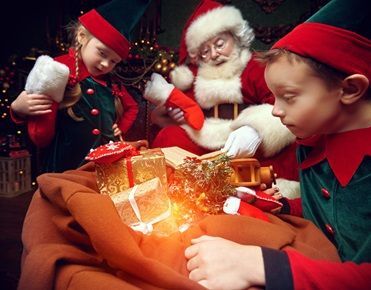Deux enfants déguisés en lutins ouvrent le sac de cadeau que leur présente le père Noël