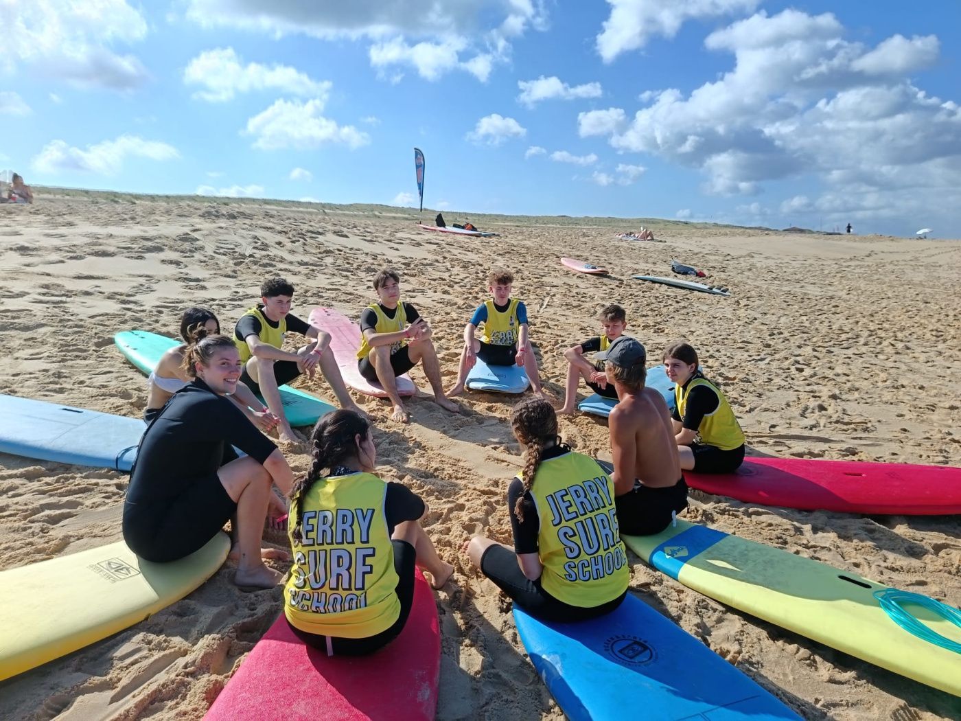 un groupe d'enfants qui sont assis sur des planches de surf sur la plage