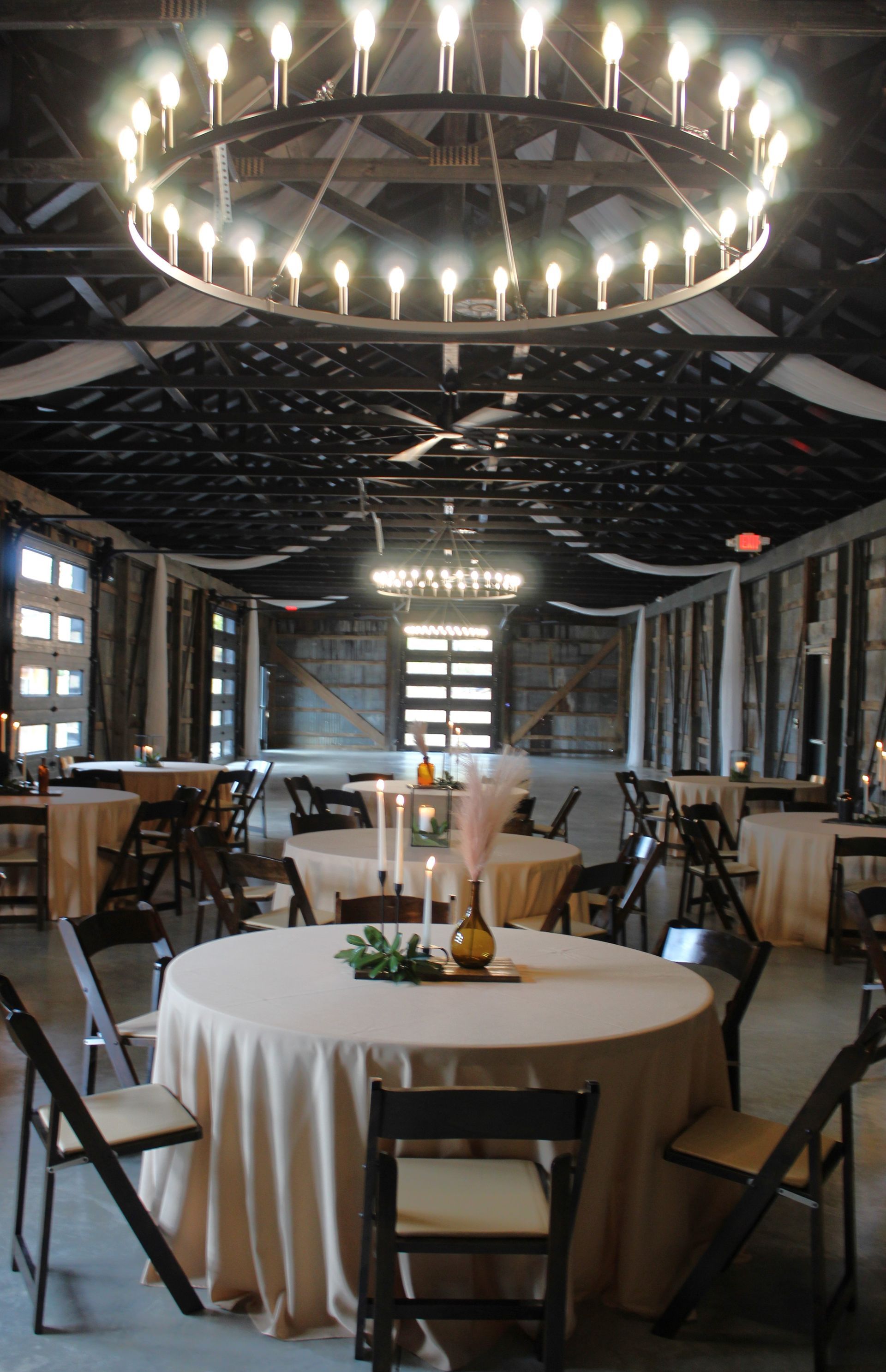 A large room with tables and chairs and a chandelier hanging from the ceiling.