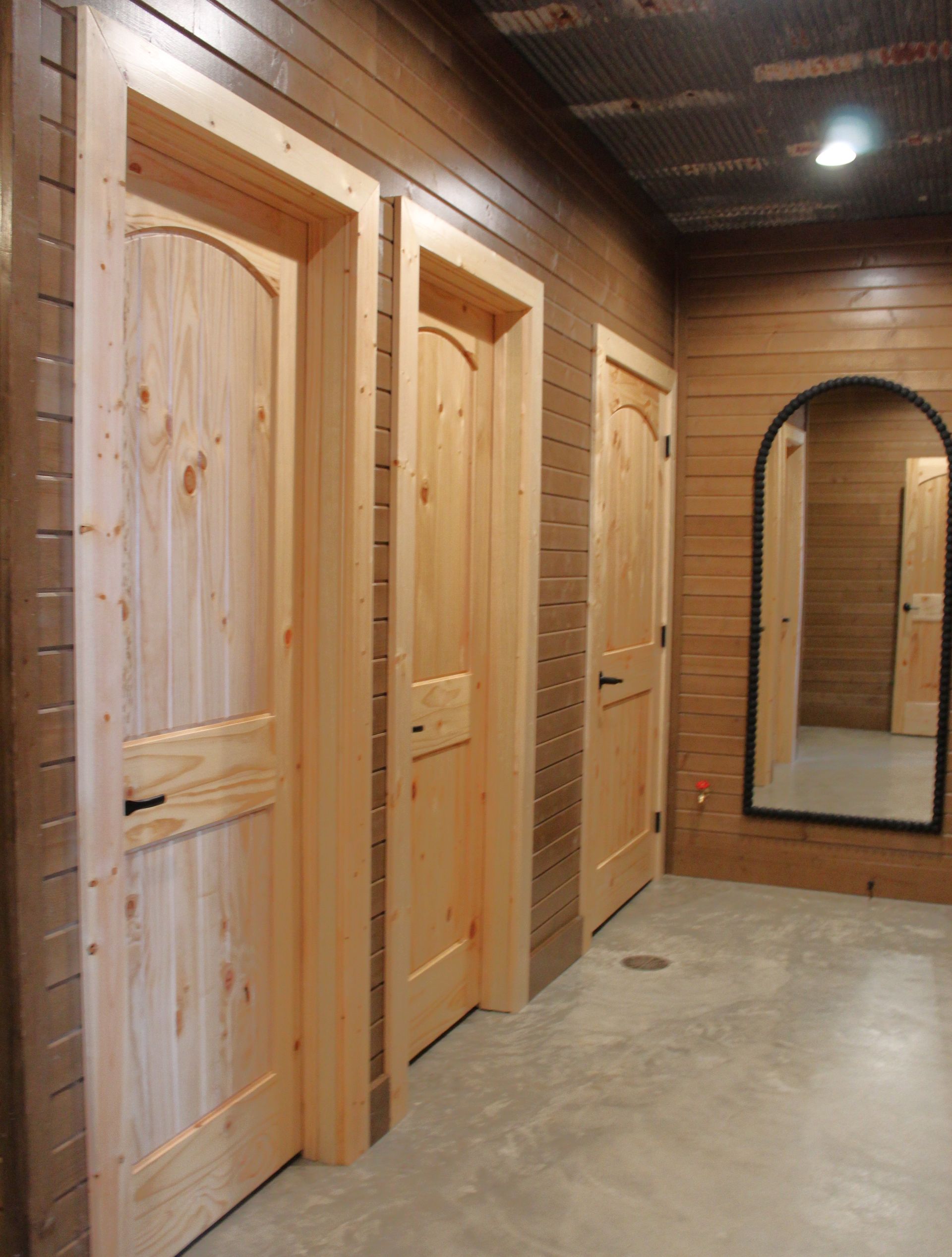 A hallway with wooden doors and a mirror on the wall